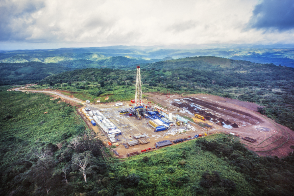 Image of a tower and drill rig in middle of a forest on an open land