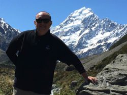 Image of person posing with snowy mountains in the background